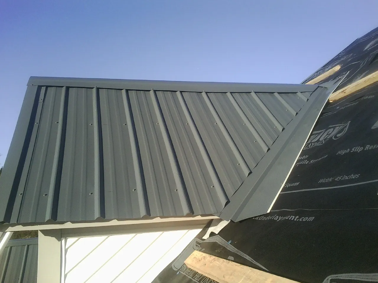 Gray metal roof panels going on over a garage gable in Gretna