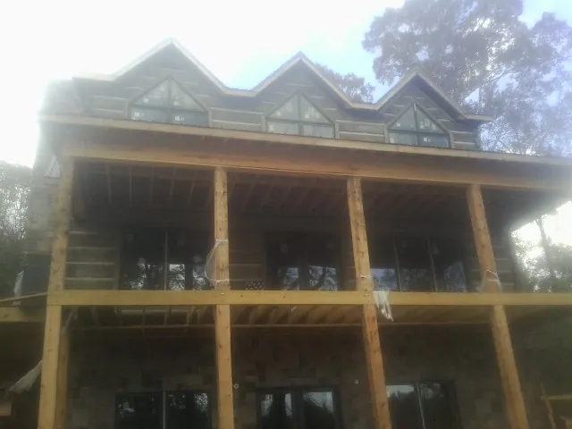 Dormers and porch framing on a large log home under construction — Roof Coating work by our crew in Gretna